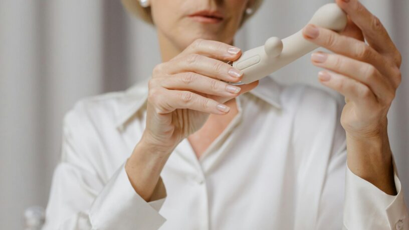 Photo par cottonbro studio A mature woman examines a cream-colored personal wellness device indoors.