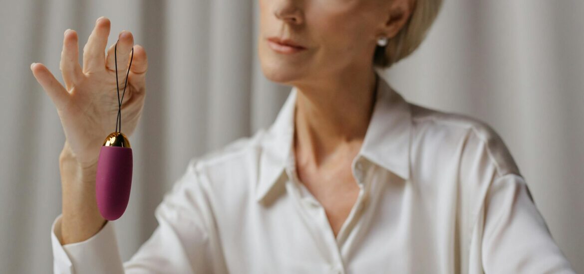 Photo by cottonbro studio Mature woman in white blouse examining a purple vibrator indoors.